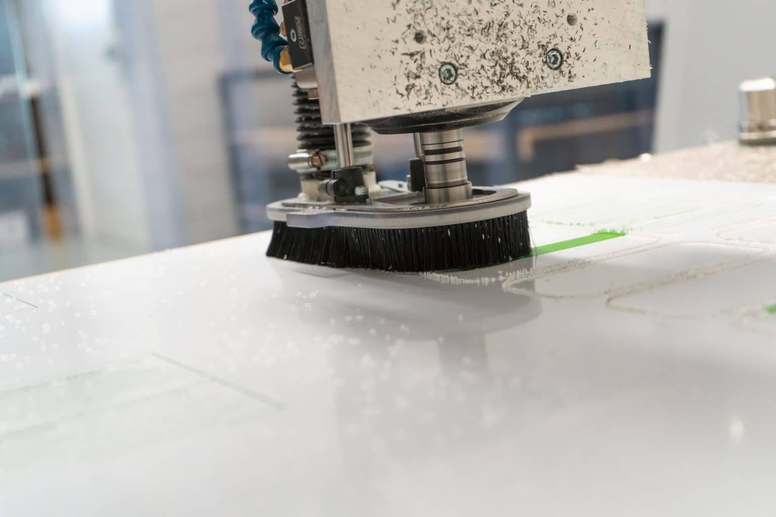 CNC-freeskop met afzuigborstel freest contouren uit een witte kunststof plaat